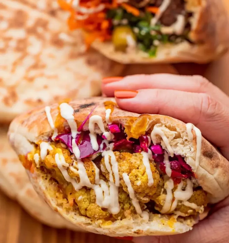 Roasted cauliflower pita with red cabbage and tahini sauce held in hand