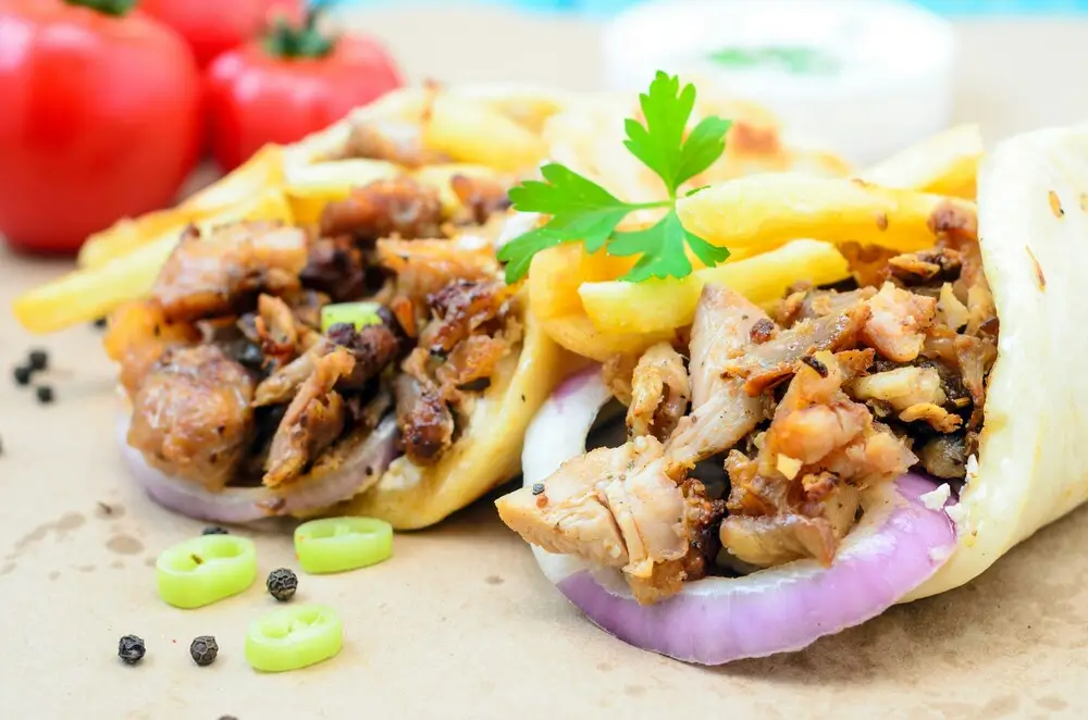 Chicken shawarma wraps with fries, red onion and parsley on flatbread